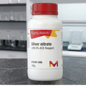 A white Silver nitrate chemical bottle with a red cap, centered against a blurred, modern laboratory background.